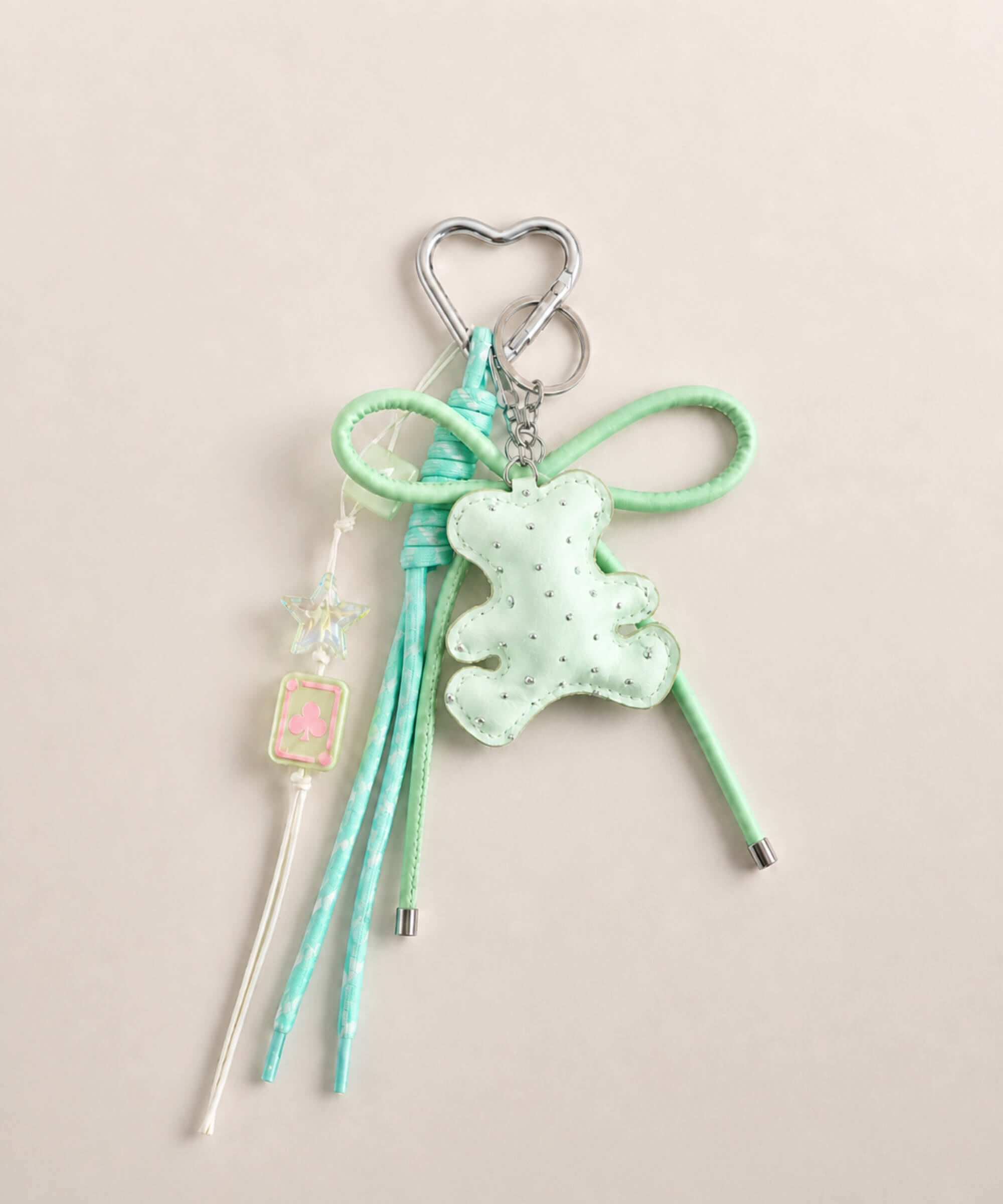 Green bear PU leather bag charm keychain with a sparkle charm, star charm and card charm on a neutral background.